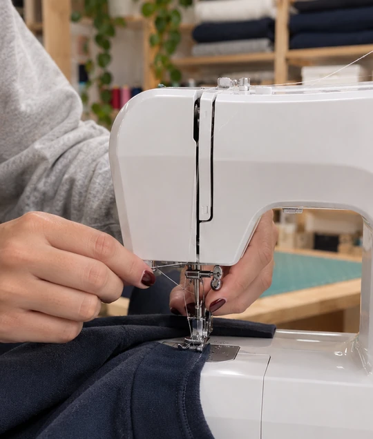 Manos de Marta cosiendo un regalo personalizado en la máquina de coser